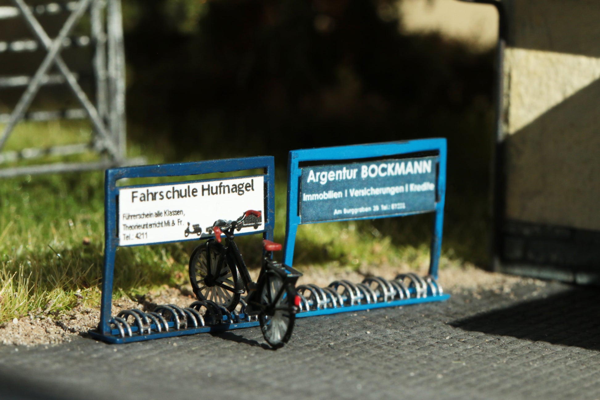 Hochdetaillierter Bausatz für Fahrradständer  mit Werbung einer Versicherungsargentur sowie einer Fahrschule maßstabsgetreu in H0 (1:87)