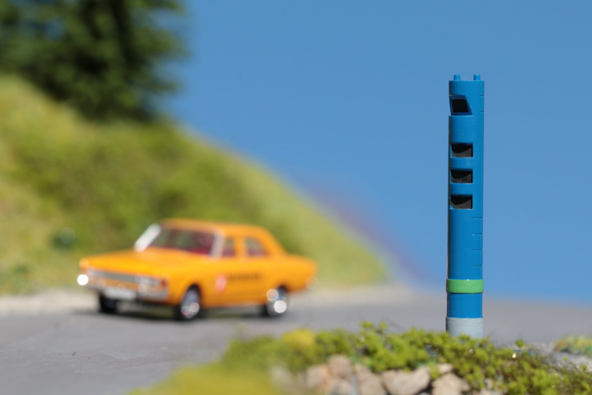 ein Ford Taununs fährt auf einer H0 Modellwelt Landschaft an einer DorrModellbau LKW Mautsäule vorbei