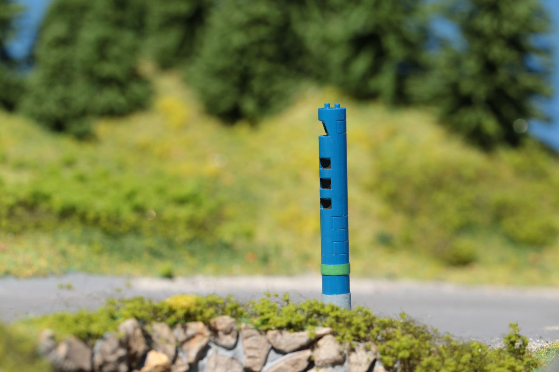 Auf einer Landstraße im Schwarzwald im Maßstab H0 steht eine detaillierte Säule für die LKW-Maut - ein Bausatz von DorrModellbau