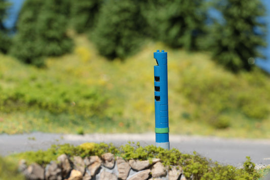 Auf einer Landstraße im Schwarzwald im Maßstab H0 steht eine detaillierte Säule für die LKW-Maut - ein Bausatz von DorrModellbau