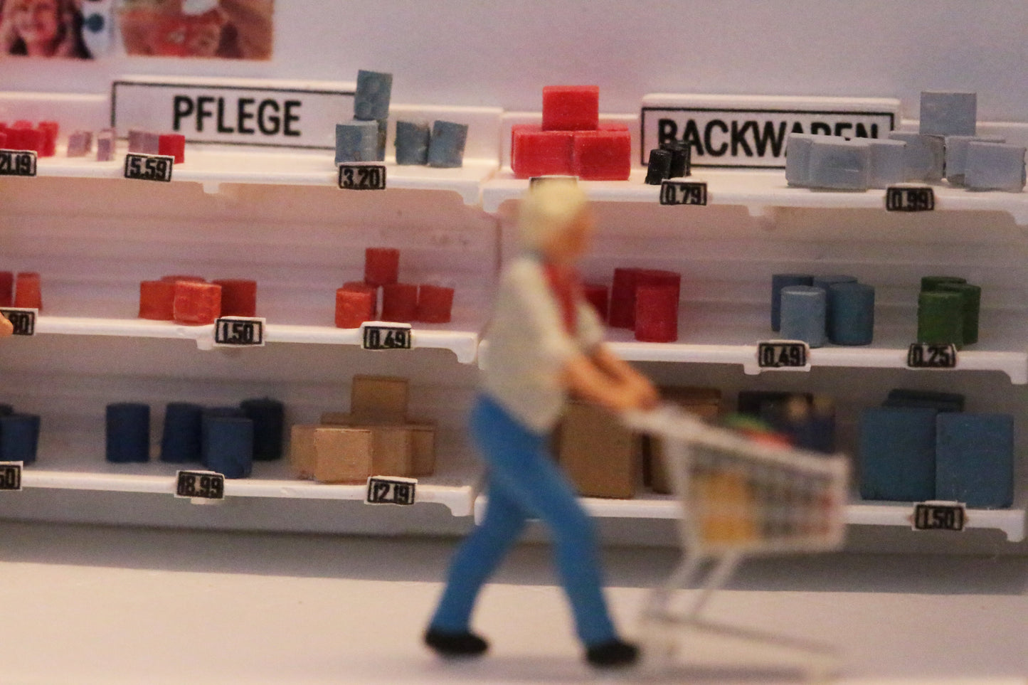 Ein Mann schiebt einen Einkaufswagen vorbei an einem Ladenregal von DorrModellbau. Detaillierte Einrichtung von Modell Häusern.