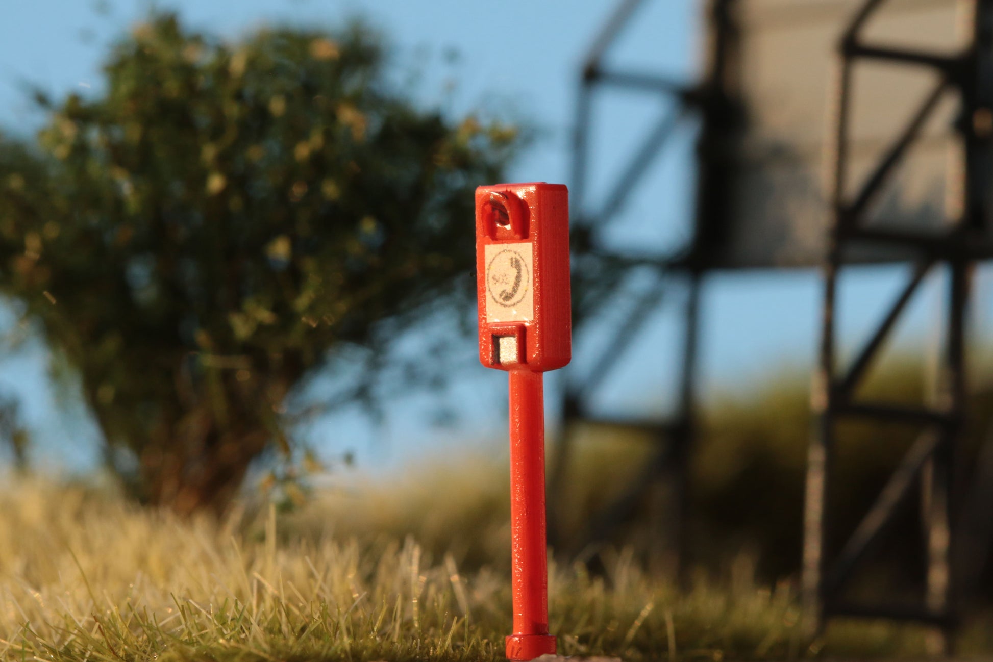Eine superdetaillierte Notrufsäule von DorrModellbau für Modelllandschaften im Maßstab H0 1:87 glänzt im Abendlicht.