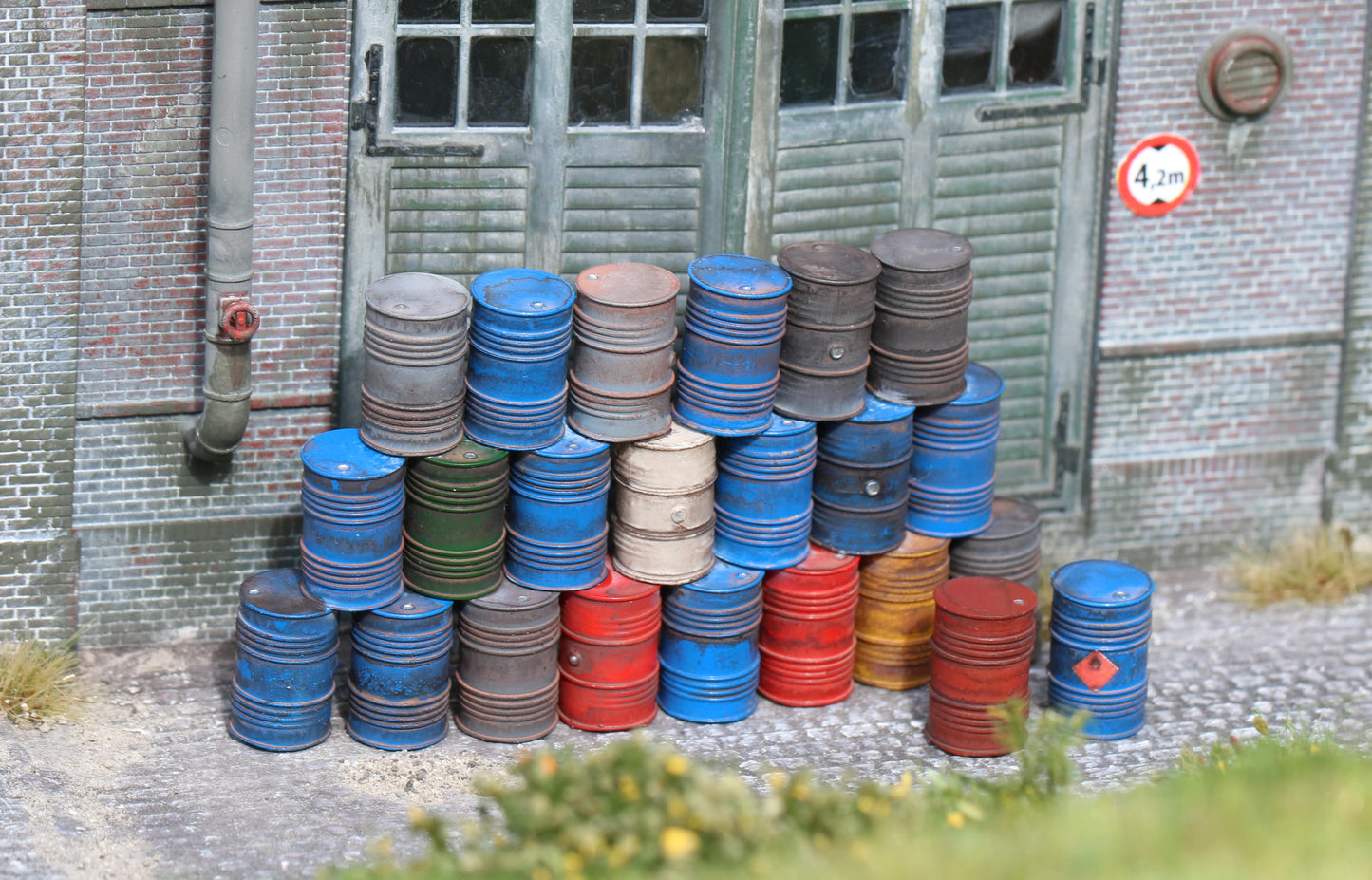 Maßstabsgetreue, detaillierte Ölfässer in H0 (1:87) von Dorr Modellbau vor einer Fabrihalle