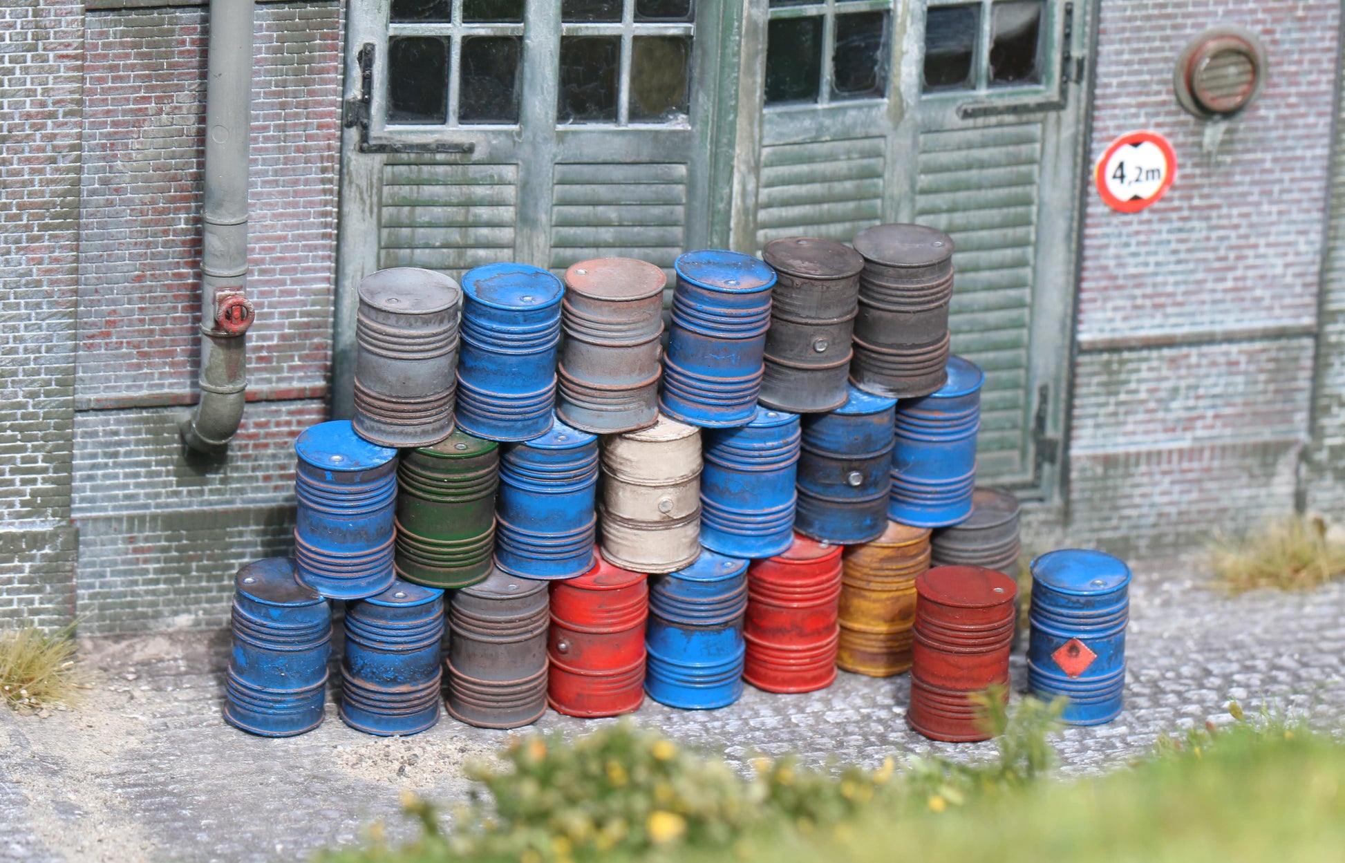 Maßstabsgetreue, detaillierte Ölfässer in H0 (1:87) von Dorr Modellbau vor einer Fabrihalle