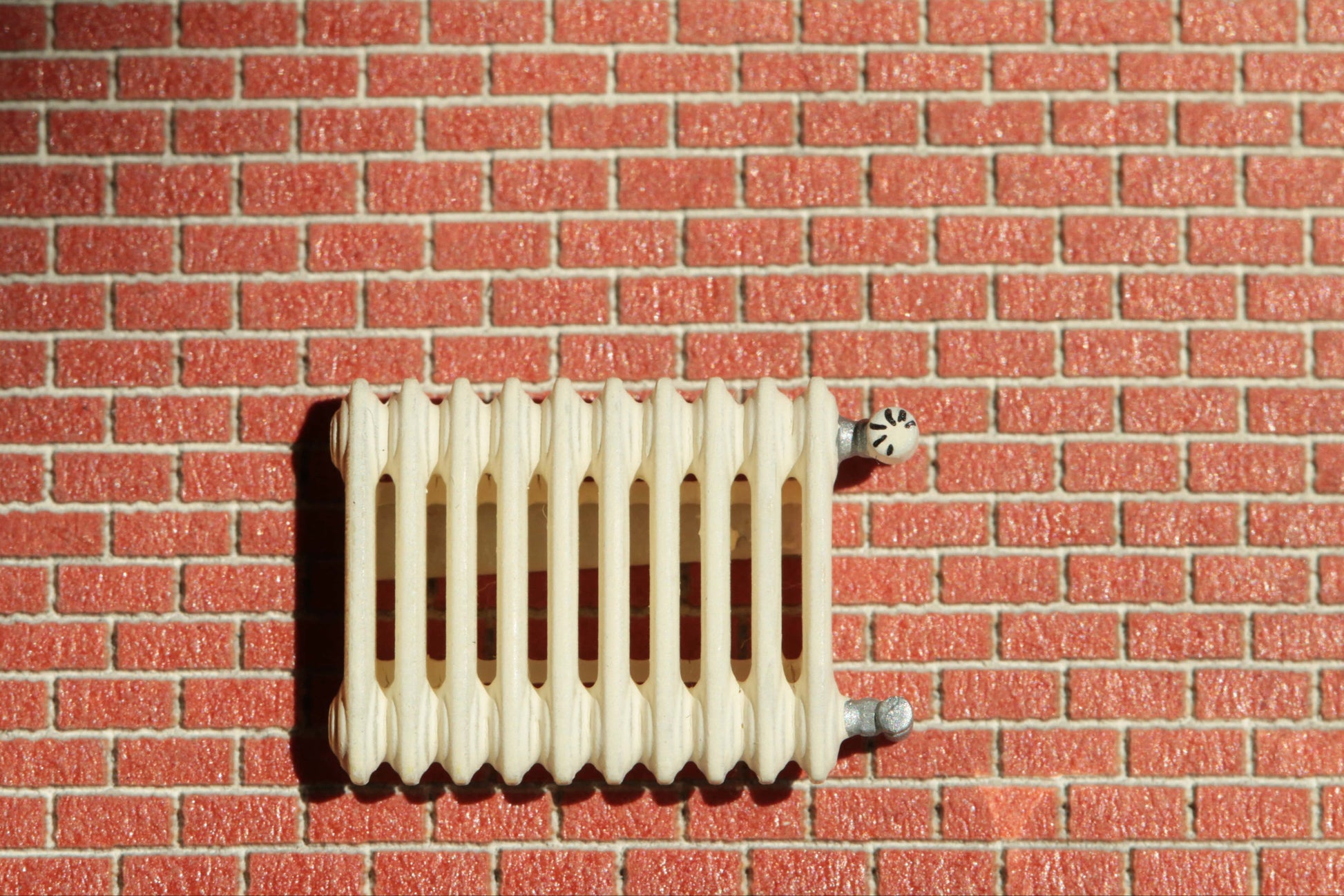 detaillierte Heizung von Dorr Modellbau im Maßstab H0 (1:87) an einer Backsteinwand auf einem Diorama einer Modellwelt