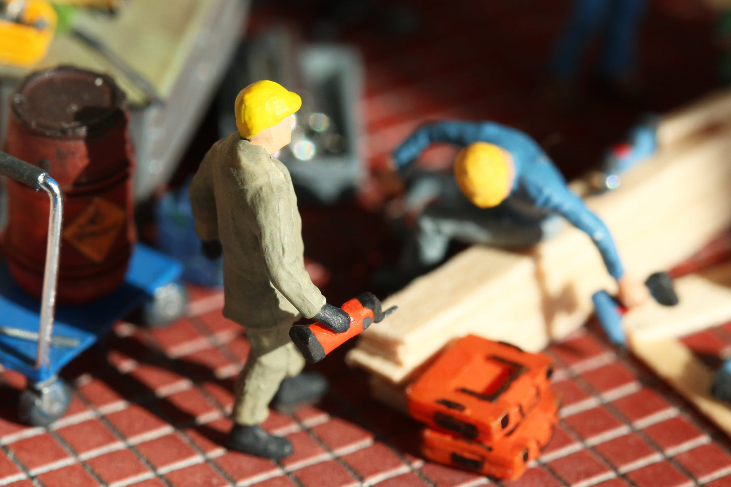 Ein Bauarbeiter trägt ein oszillierendes Multifunktionswerkzeug auf einer Modellbaustelle im Maßstab H0 1:87