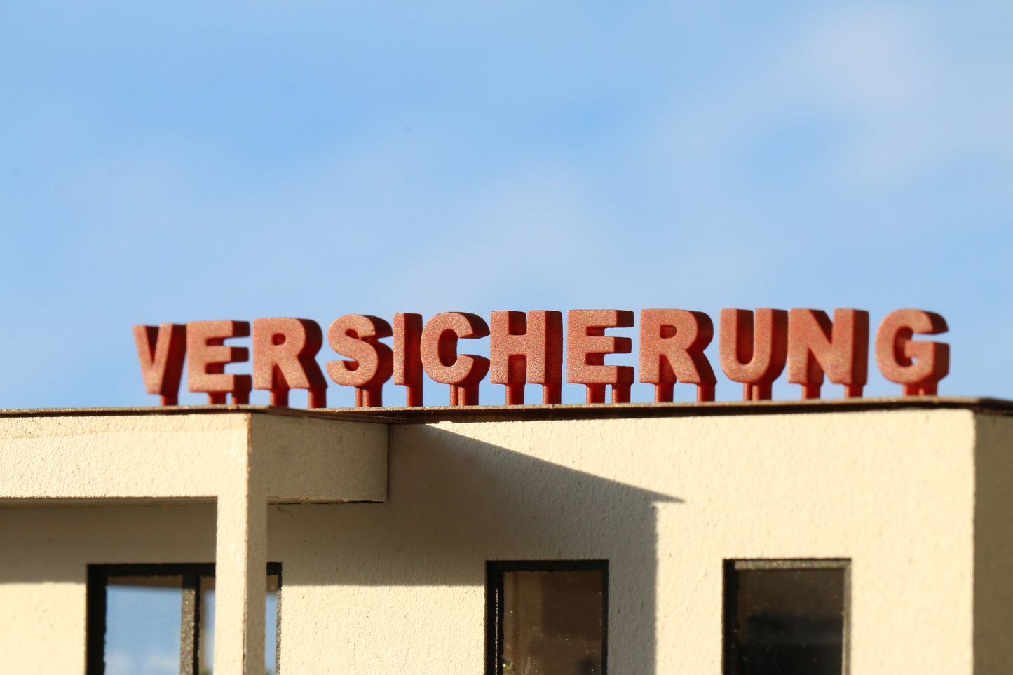 Auf einem H0 Gebäude stehen die DorrModellbau Buchstaben als Werbung für eine Versicherung