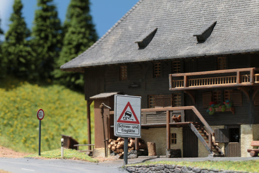 Schild für eine Gefahrenstelle mit Schnee und Eisglätte von DorrModellbau vor der Faller Ölermühle im Maßstab H0 1:87