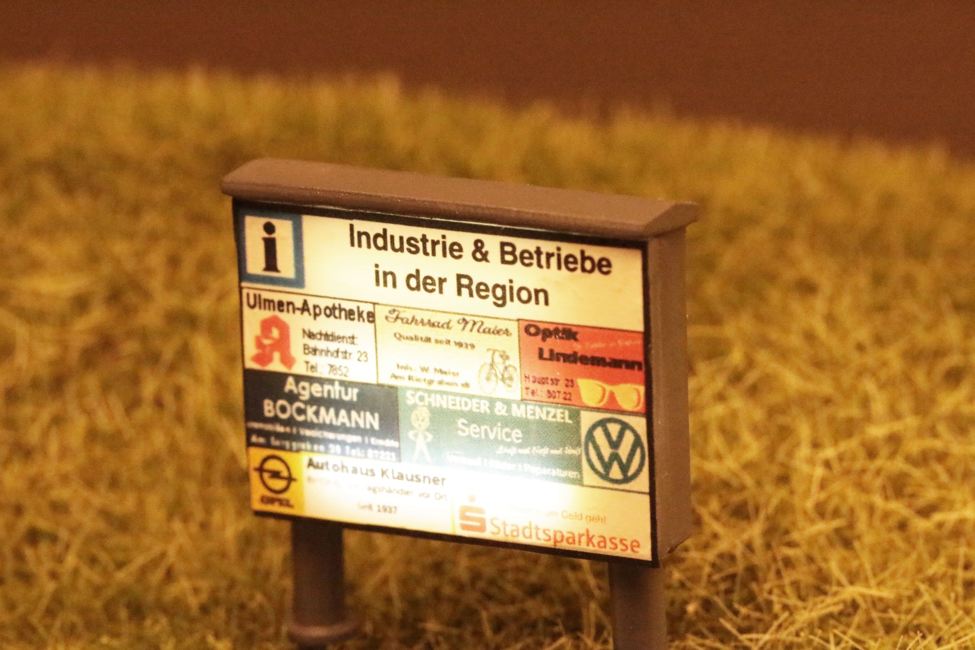 Die Informationstafel von DorrModellbau im Maßstab H0 wird bei Nacht von drei Leuchtstoffröhren beleuchtet