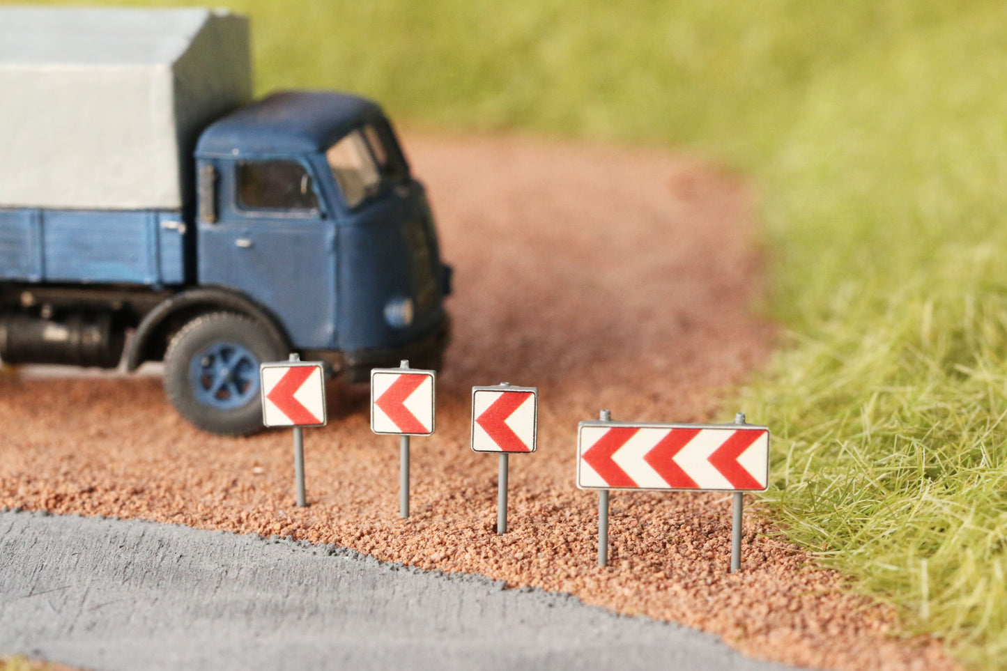 Richtungstafeln von DorrModellbau stehen vor einem Parkplatz auf einer H0 Modellbahnanlage