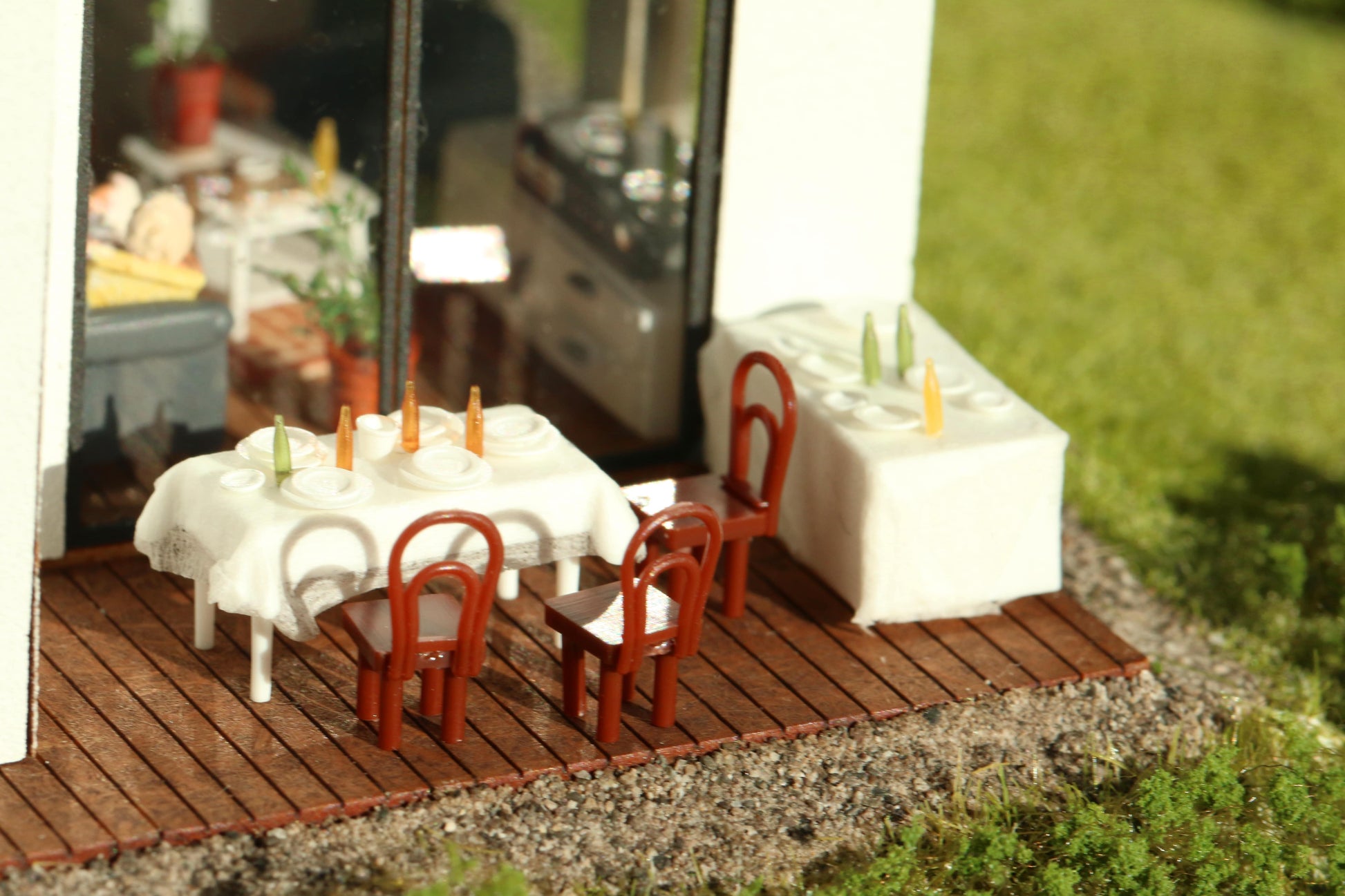 Zwei Tische sind stehen gedeckt mit DorrModellbau Tellern auf der Terrasse eines Modellhauses.