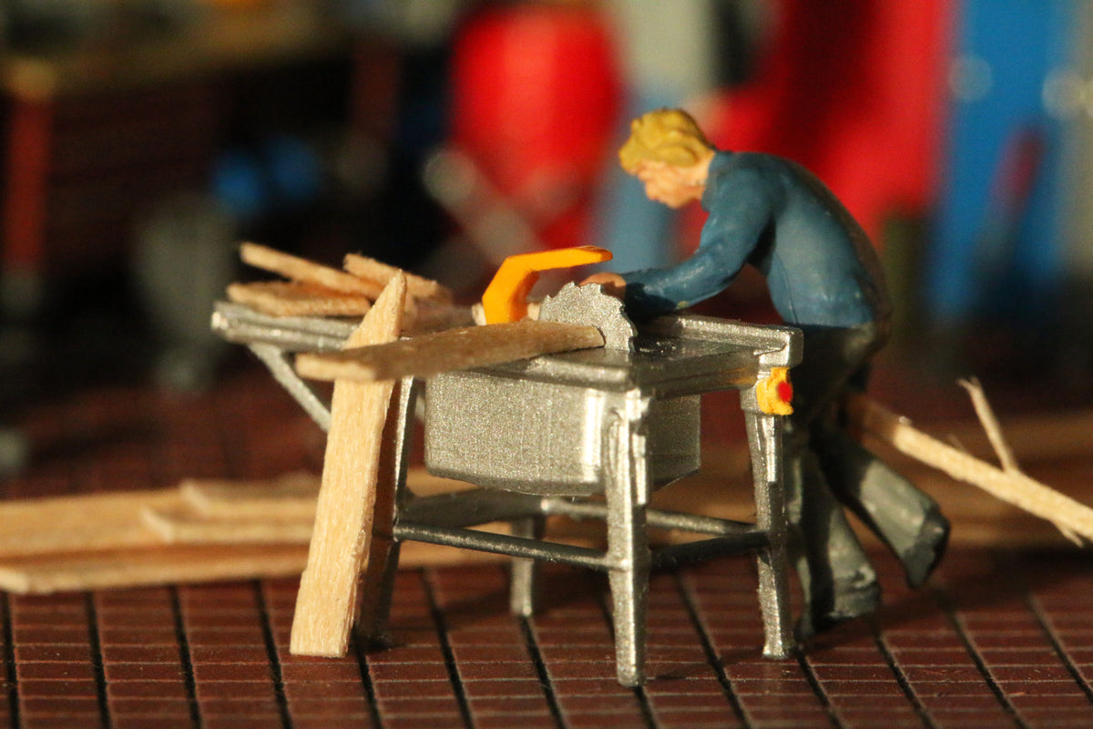 Ein Arbeiter sägt Bretter an der Tischkreissäge im Maßstab H0 1:87 von Dorr Modellbau.