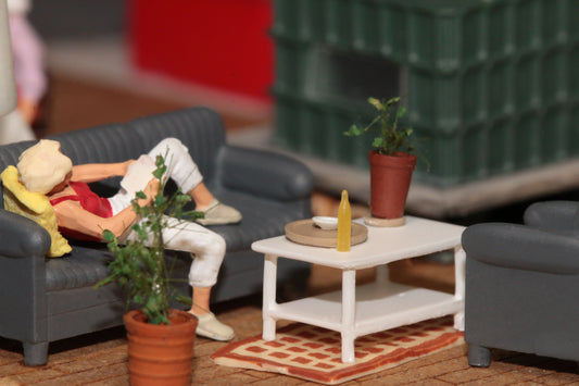 Eine Frau liegt lesend auf einer Couch von DorrModellbau im Wohnzimmer eines Modellhauses