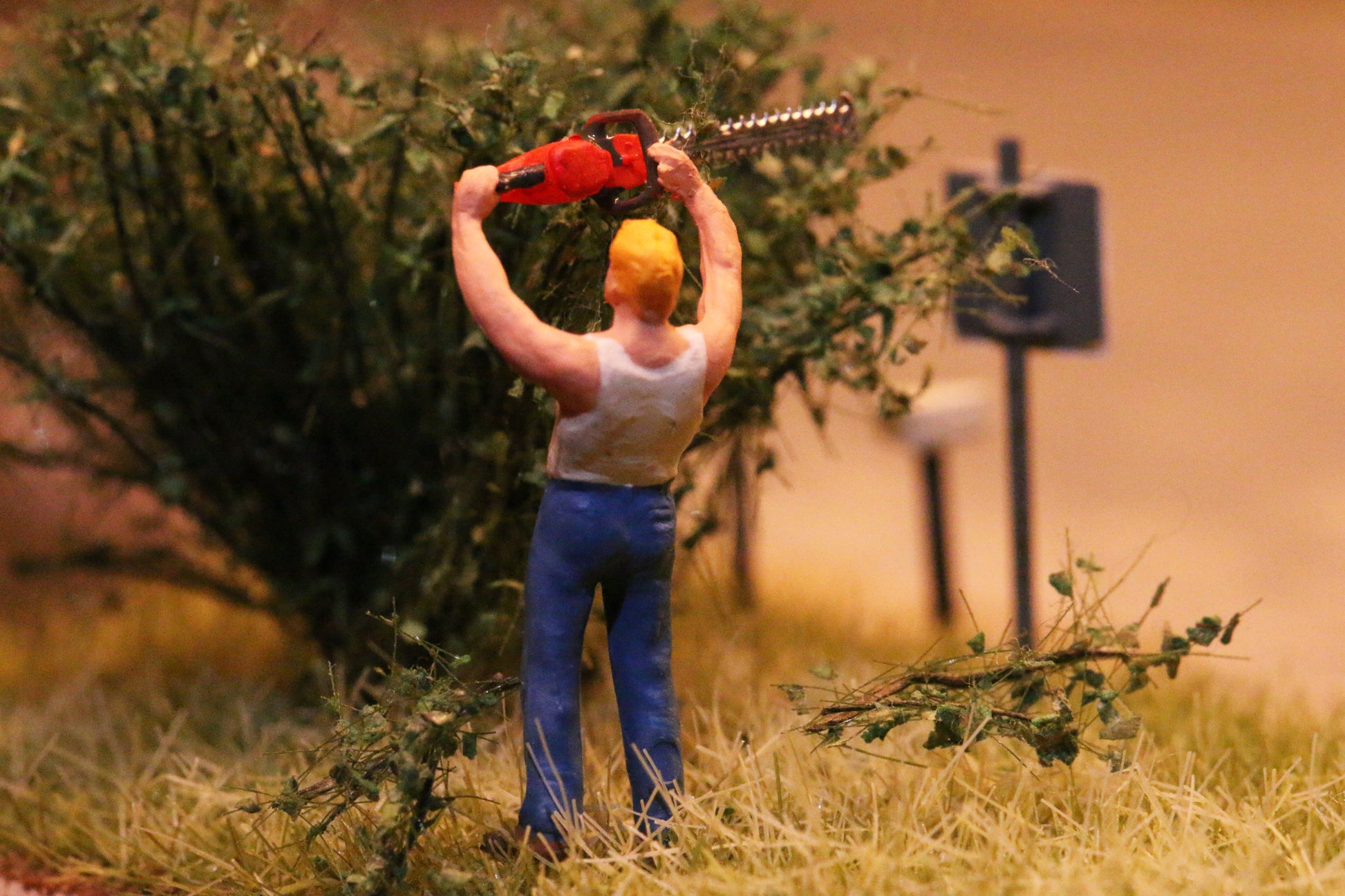 Eine Modellfigur im Maßstab H0 1:87 schneidet mit einer Heckenschere von DorrModellbau einen Busch.